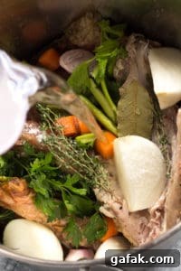pouring water over turkey broth ingredients in a large pot