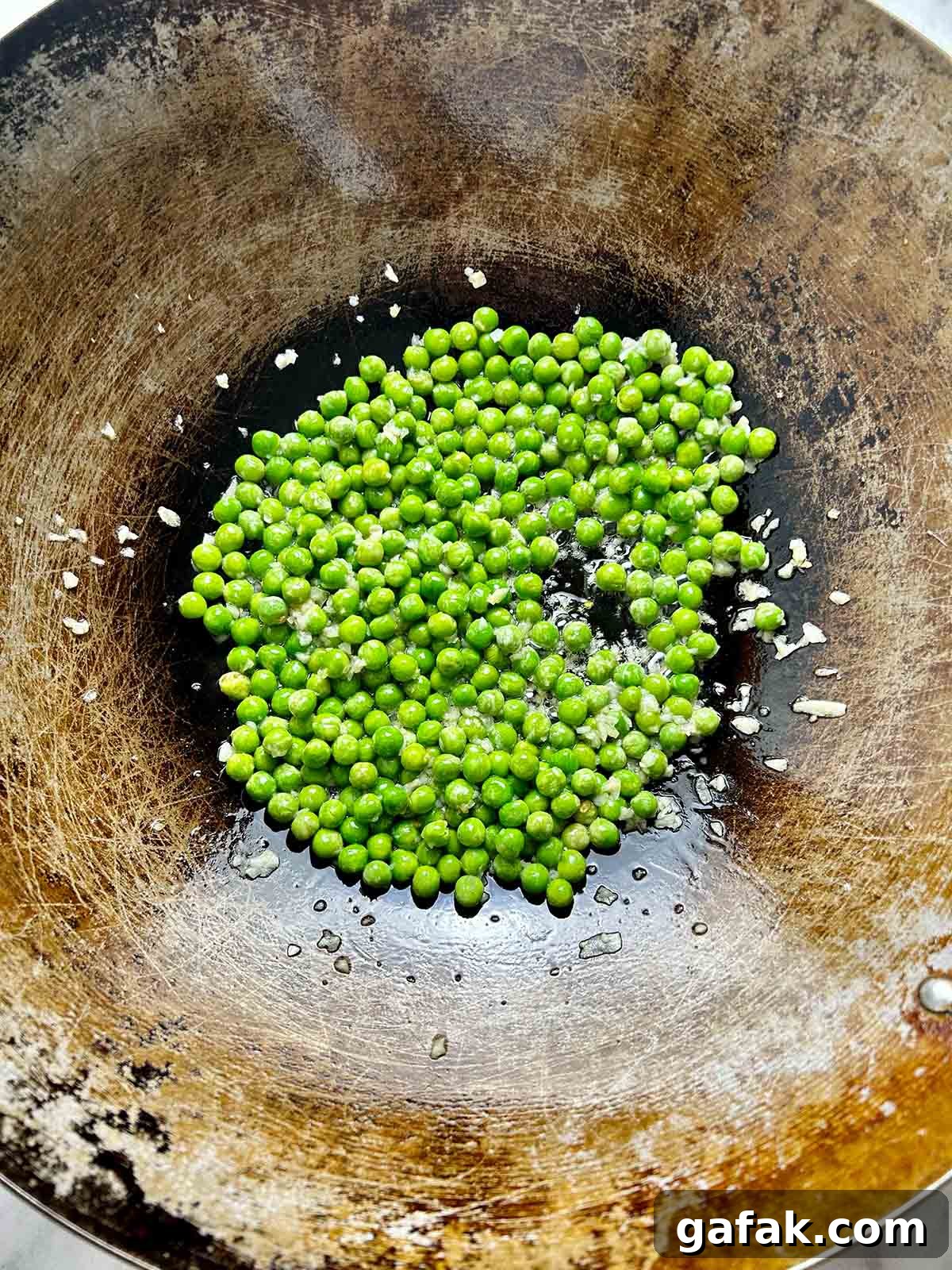frying peas and garlic in wok