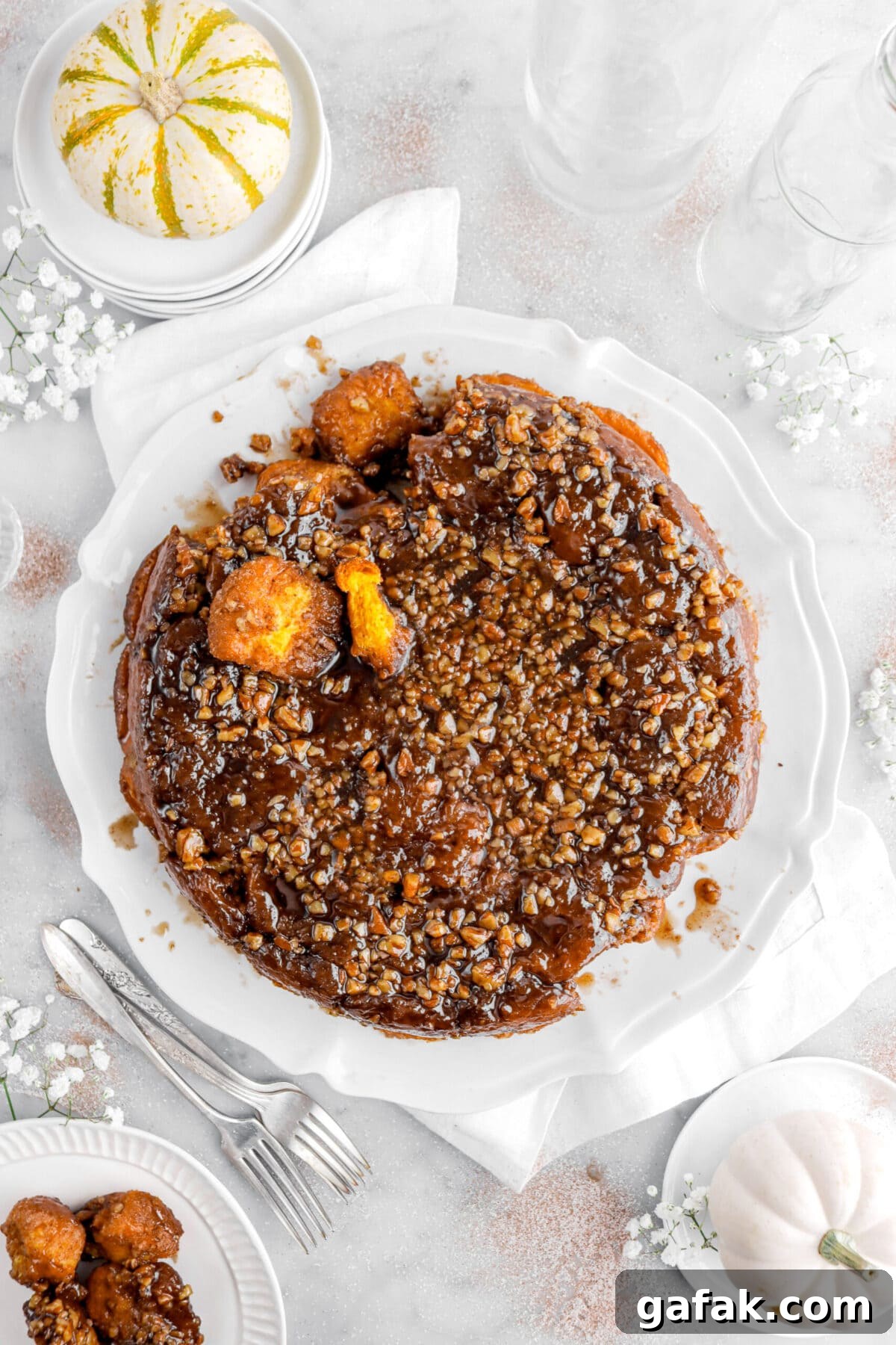 monkey bread with pieces taken apart on white plate with flowers and forks around.
