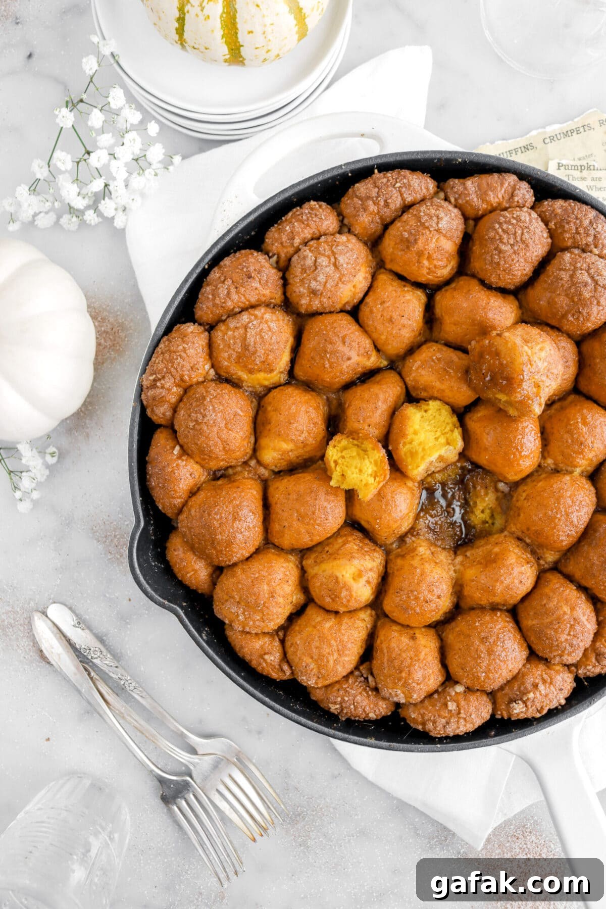 cropped overhead image of pumpkin monkey bread in skillet with pumpkins around.
