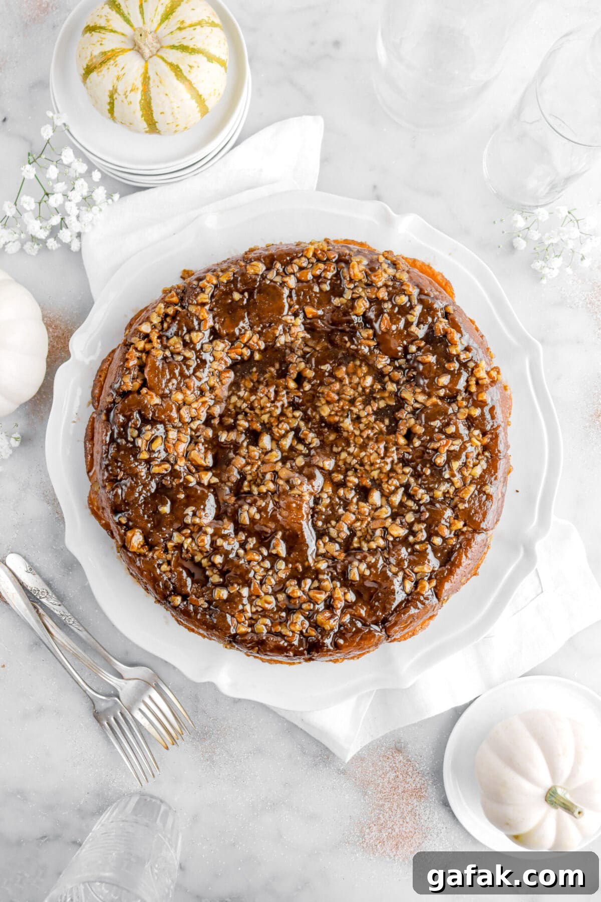 overhead image of monkey bread on white plate with white flowers and pumpkins around.