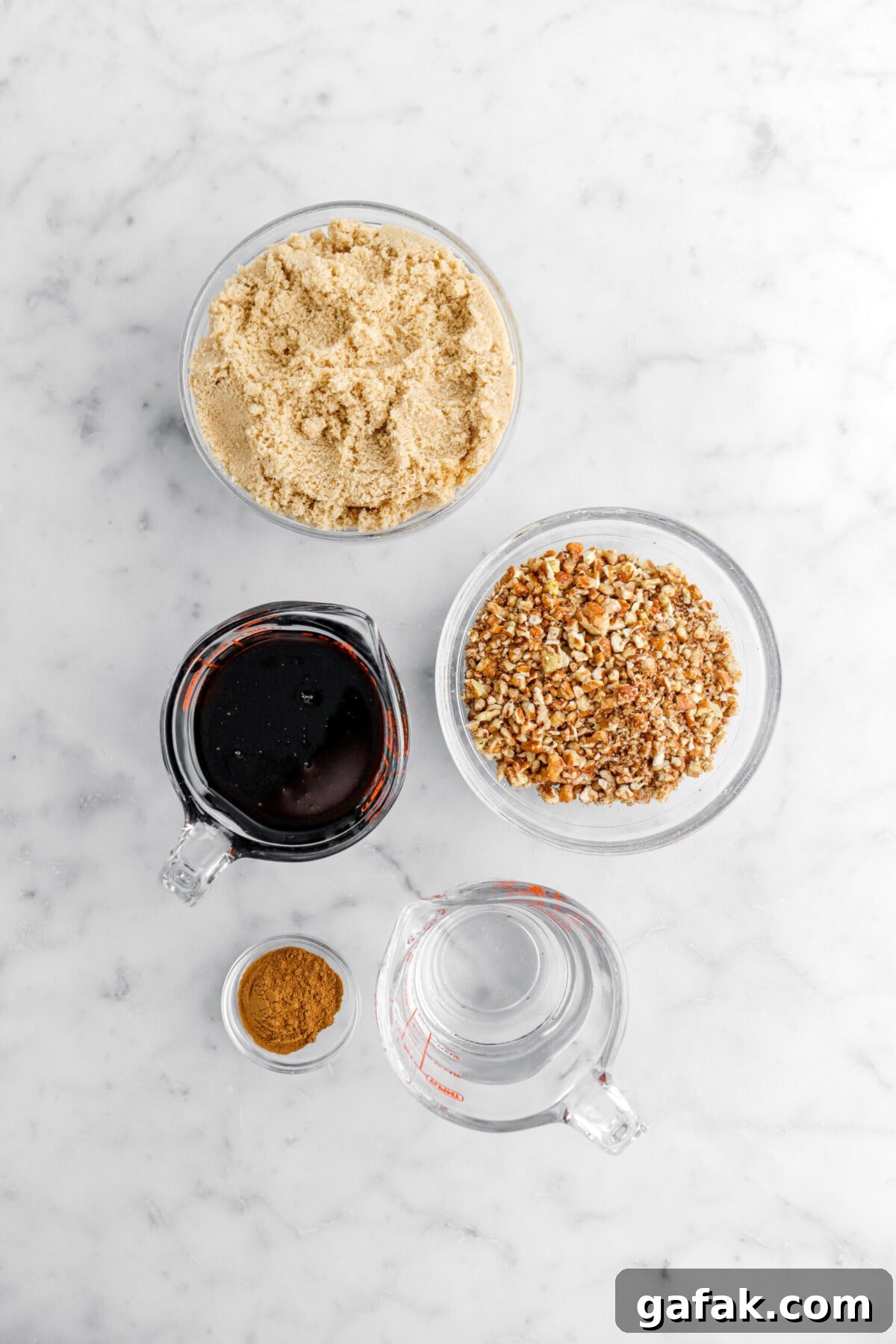 brown sugar, chopped pecans, dark corn syrup, ground cinnamon, and water on marble surface.