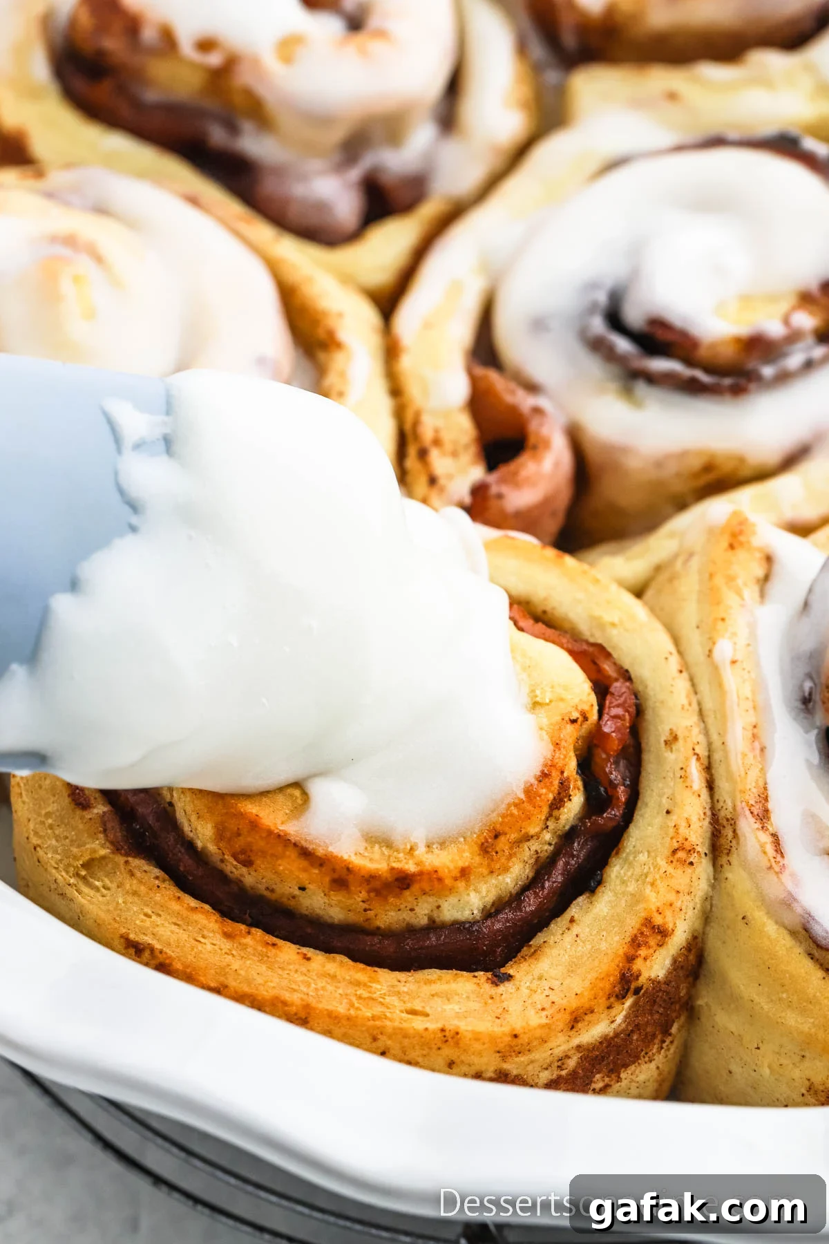 Icing being added to cinnamon rolls. 