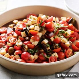 Tomato salad with mozzarella and basil in serving dish on table.