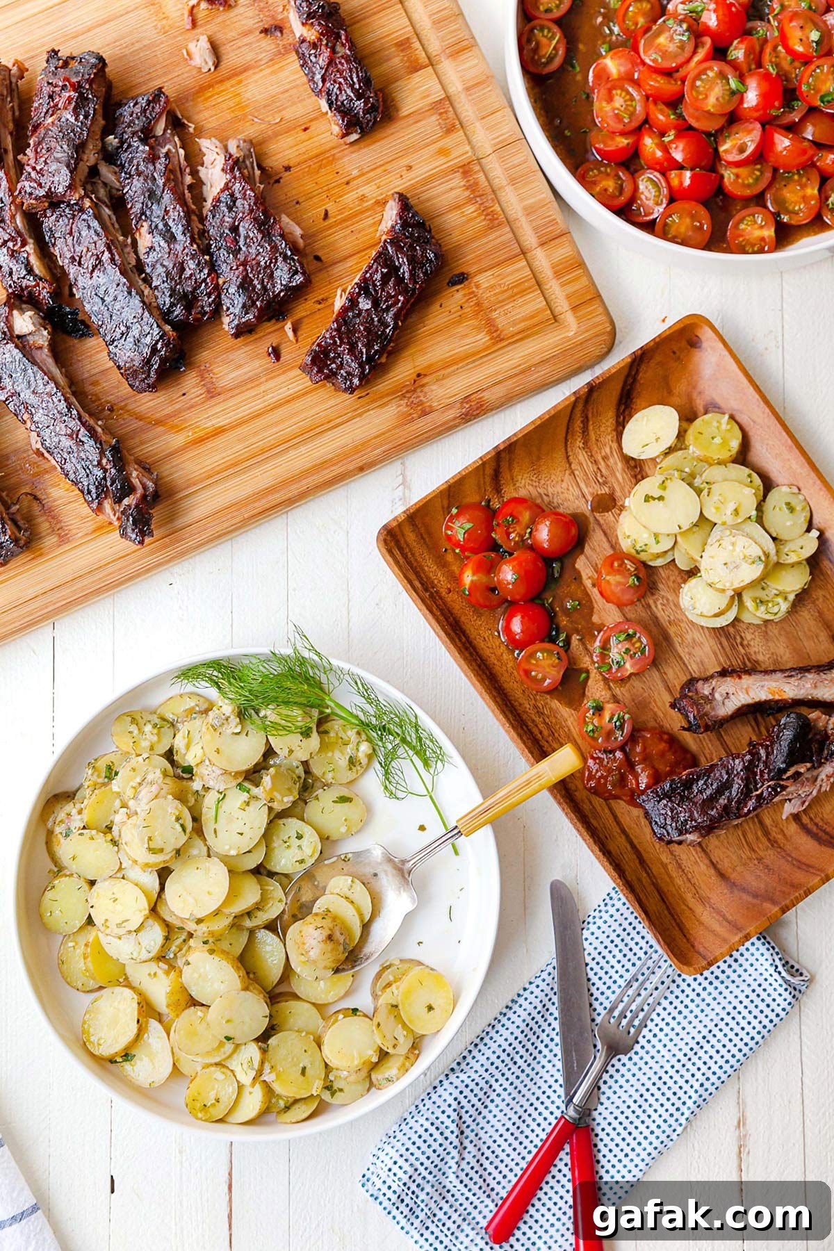 Wood table with Cherry Tomato Salad, French potato salad, and Cajun ribs.