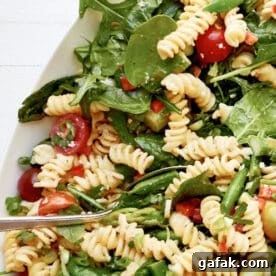 Simple Vegetarian Spring Pasta Salad in white serving platter with spoon.