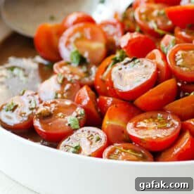 Freshly made cherry tomato salad with homemade vinaigrette in white serving bowl.