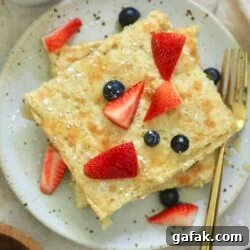 plate with square shaped pancakes and fruit on top.