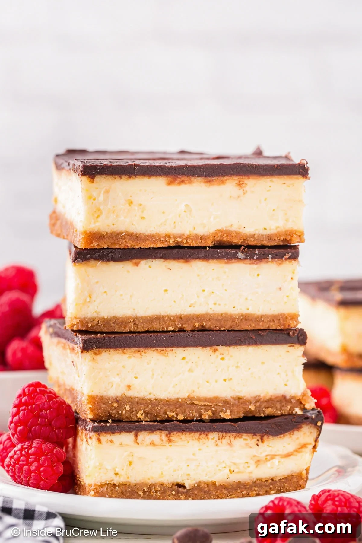 Creamy No-Bake Cheesecake Bars Recipe for Parties 6 A stack of four cheesecake bars on a white plate.