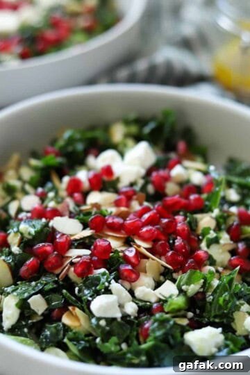 close up of kale salad topped with pomegranate seeds