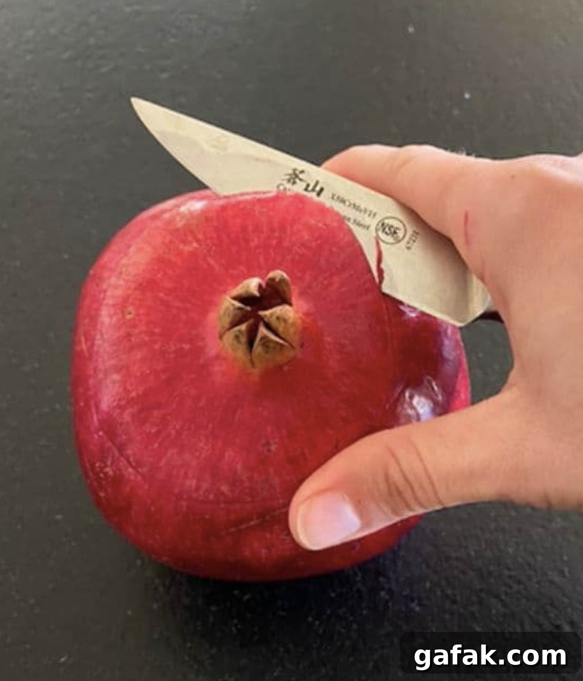 Opening pomegranate top with knife.