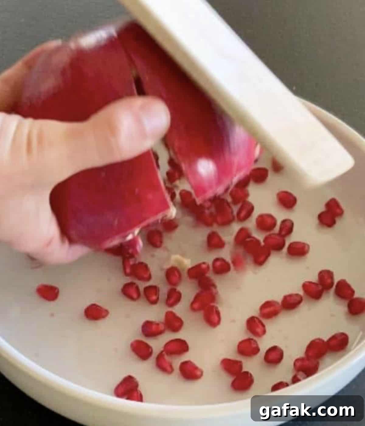 Wooden spoon hitting pomegranate.