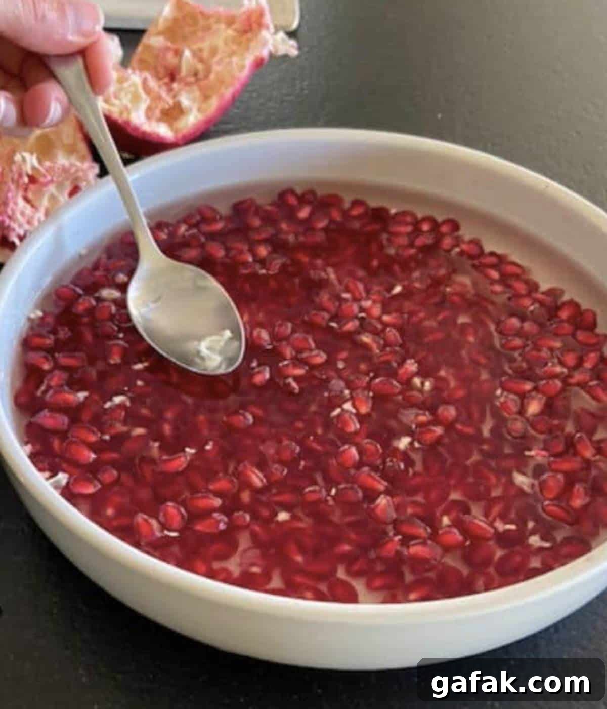 Spoon removing membranes from seeds in water.