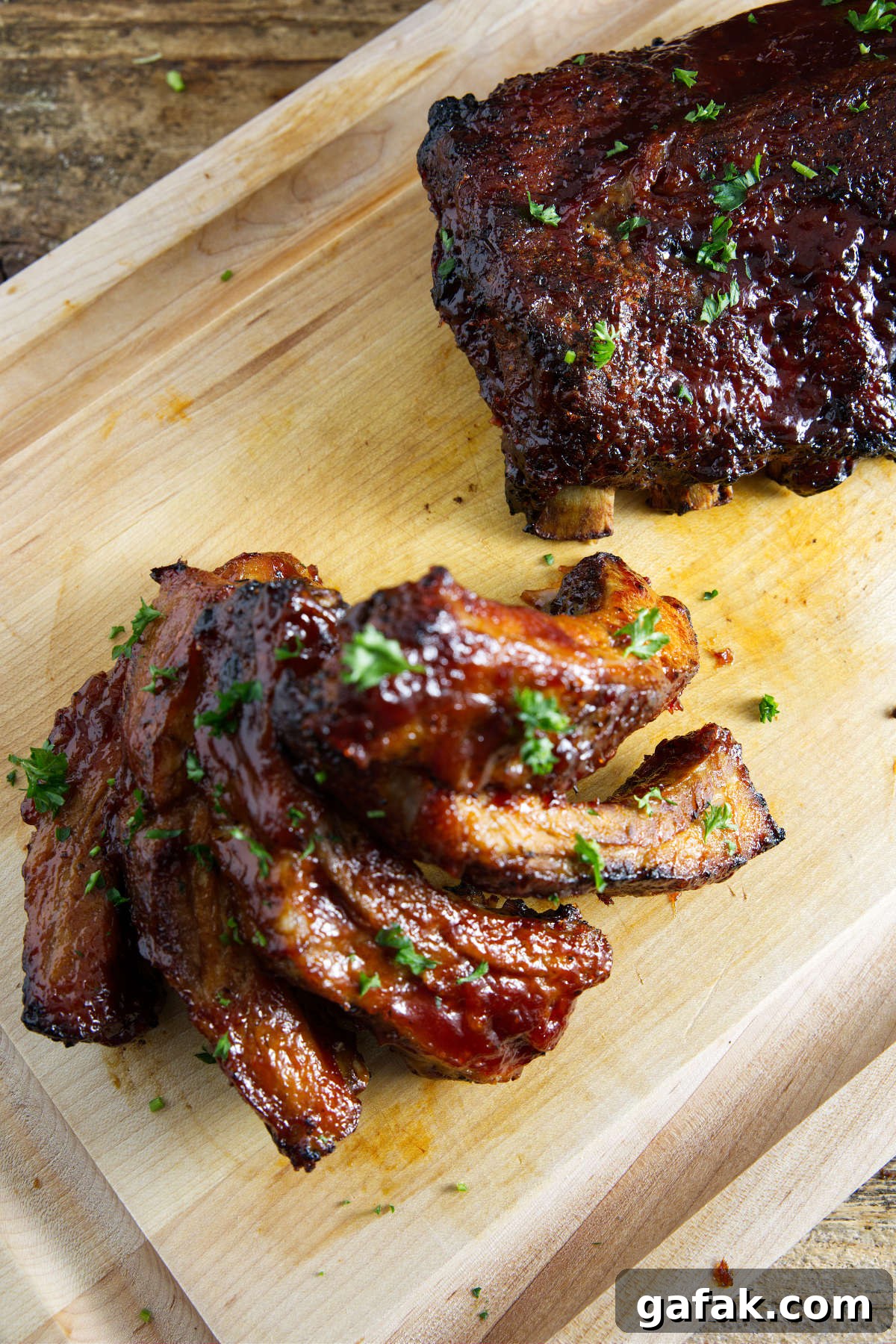 Slab of pork ribs and a stack of individually sliced ribs on the cutting board.
