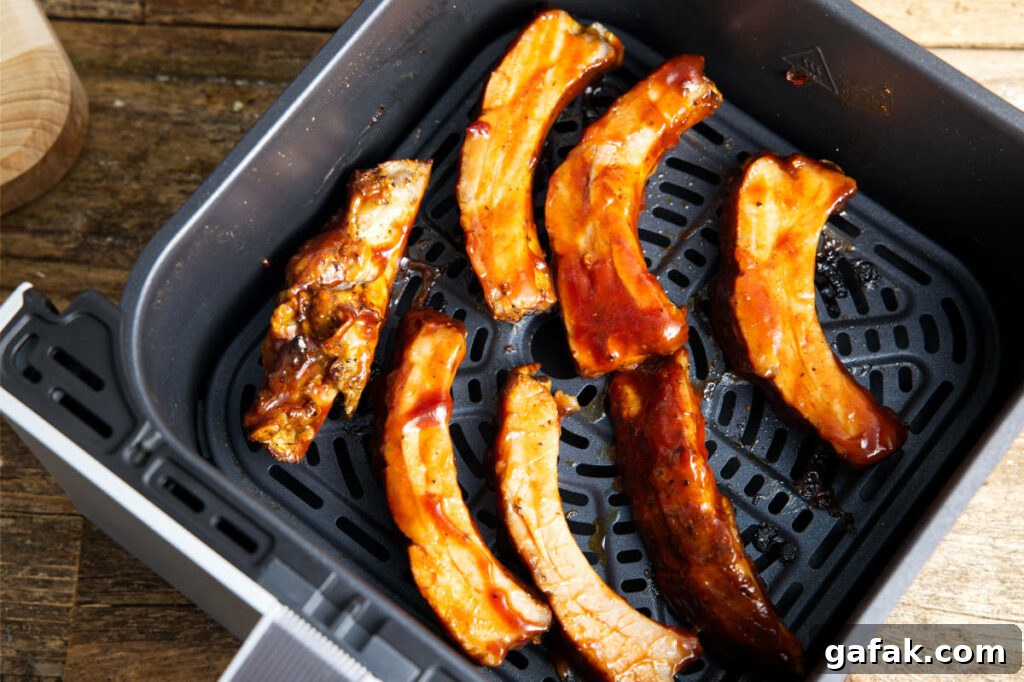 Sauce individual pork ribs in the air fryer basket.