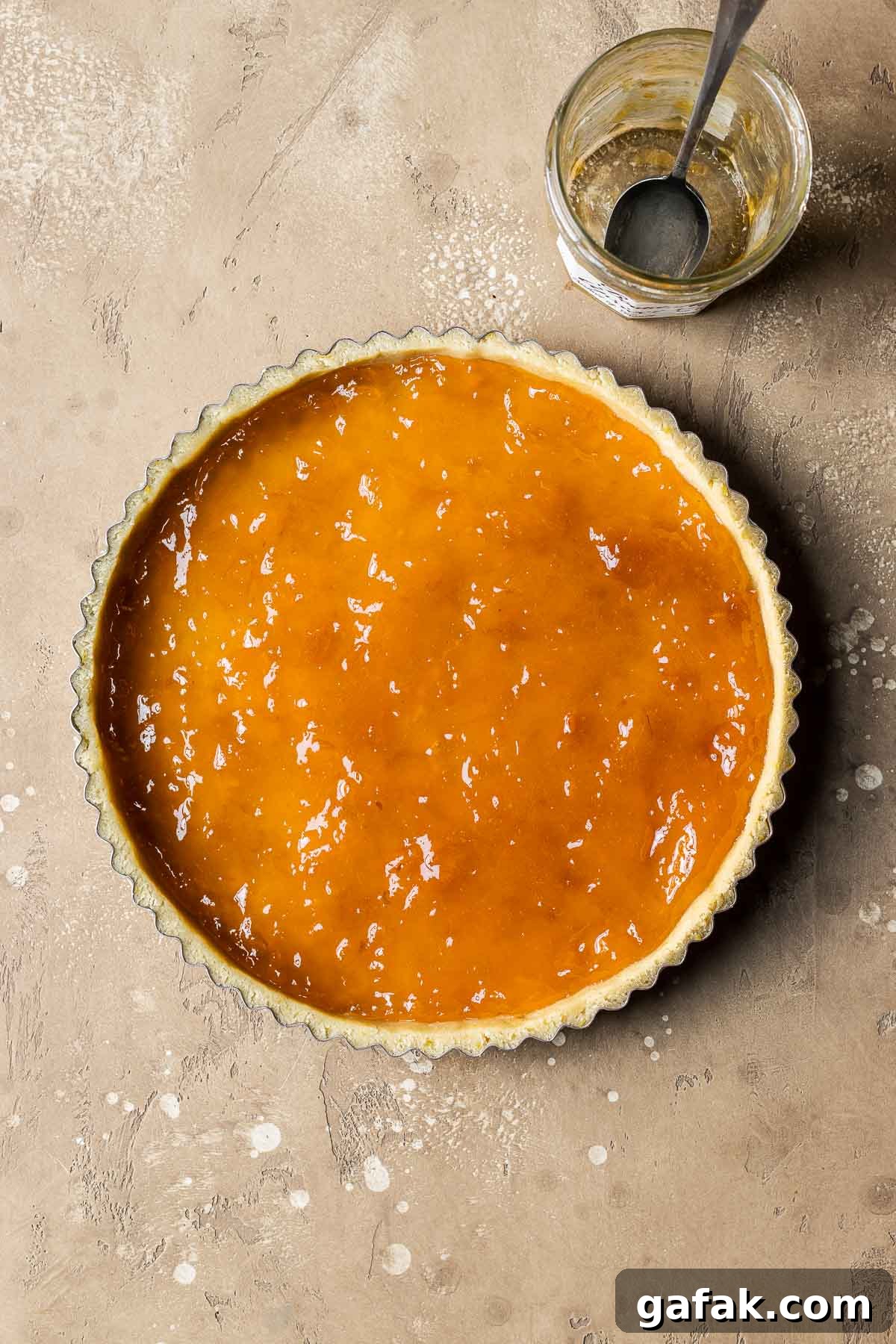 An unbaked tart shell filled with apricot jam.