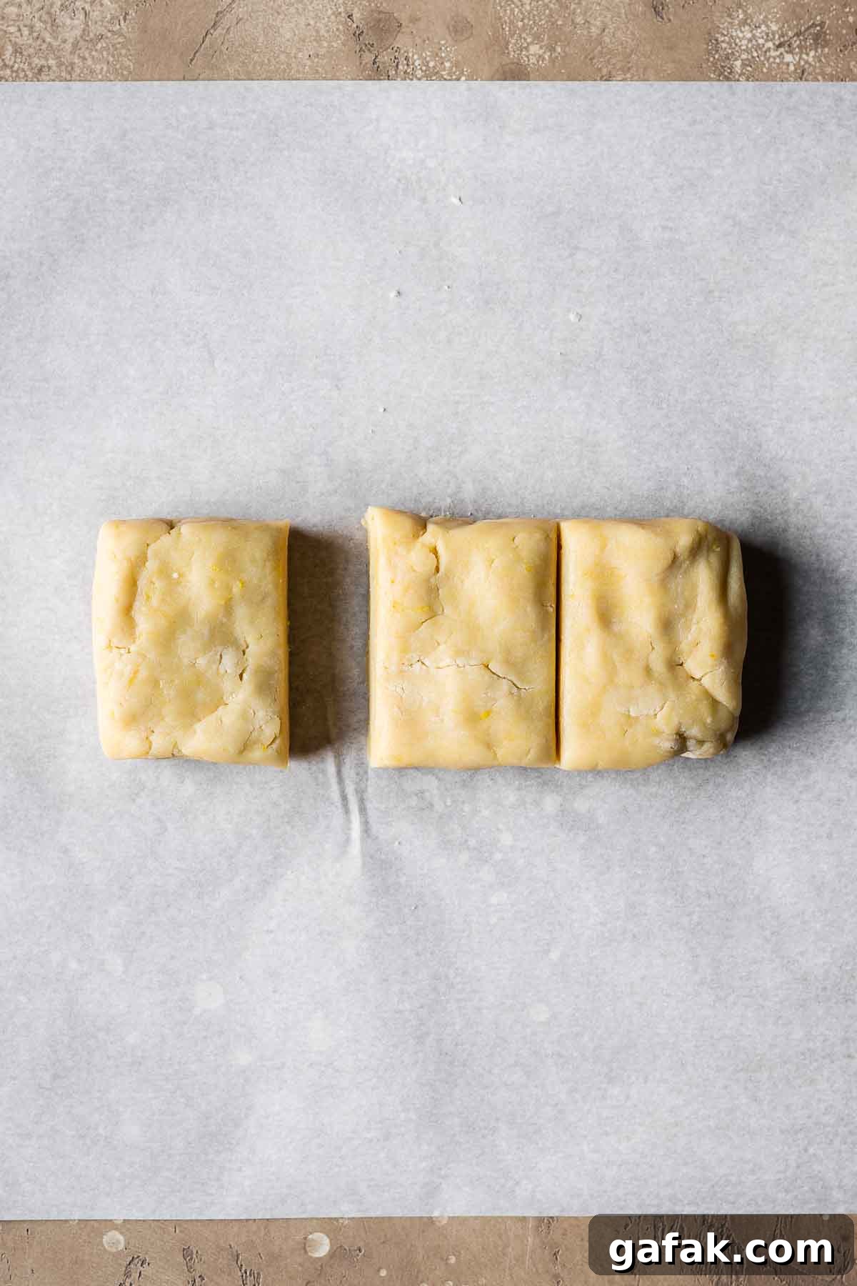 Shortcrust pastry dough divided into thirds on parchment paper.