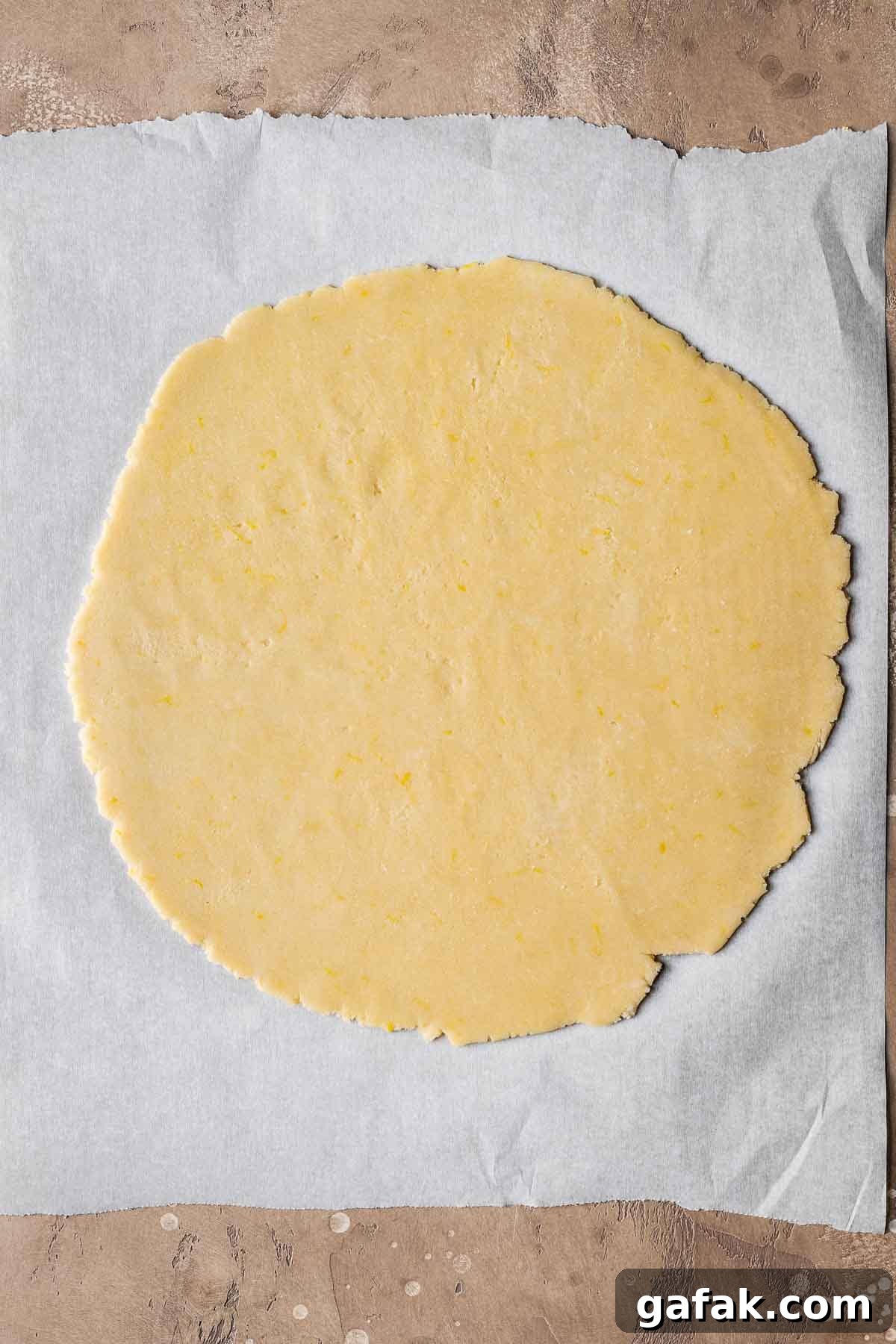A circle of rolled pastry dough on white parchment paper.