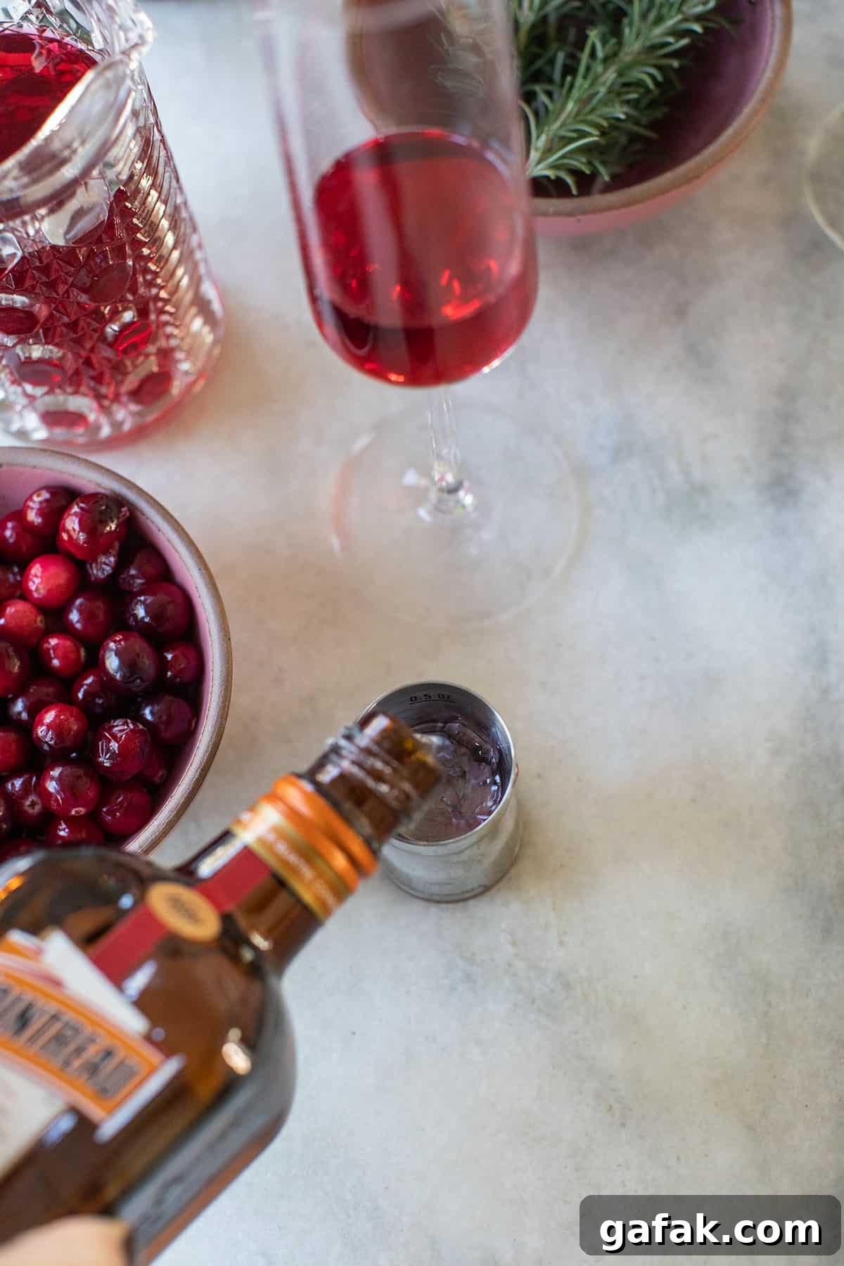 Pouring orange liqueur into a cocktail jigger.