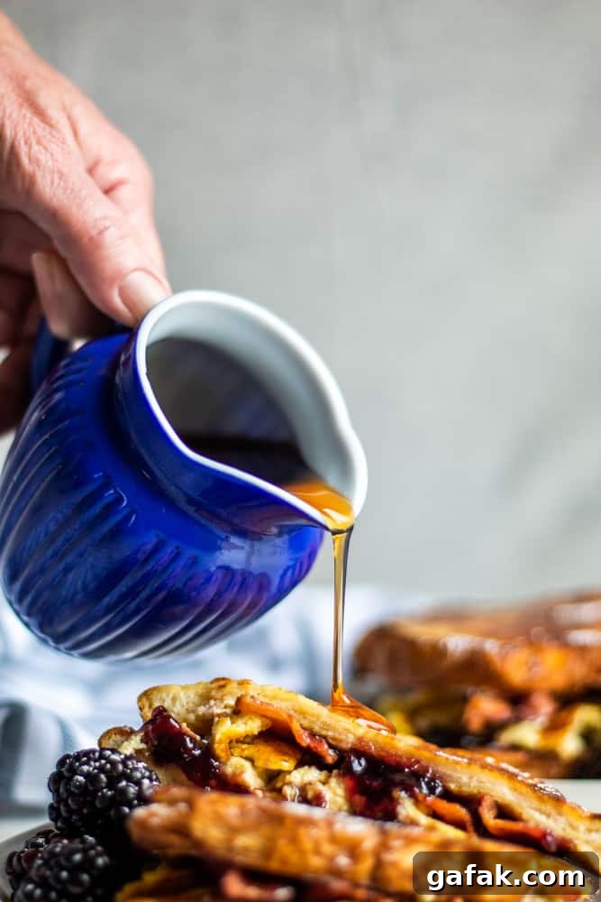 Hand pouring maple syrup over stuffed french toast.