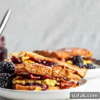 French toast sandwich on a white plate with gray background and second plate in the background.