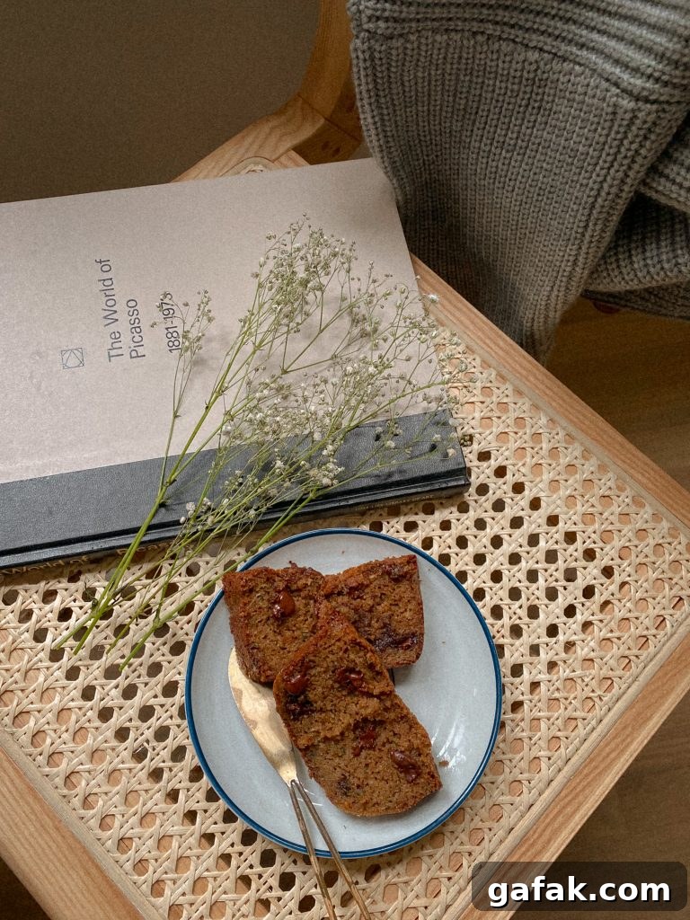 Gluten-Free Dairy-Free Zucchini Bread Recipe 4 2 slices of zucchini bread on a plate with white flowers and a book on a chair