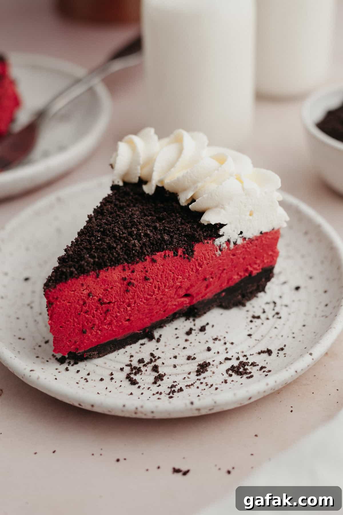A slice of red velvet oreo cheesecake on a small white plate.