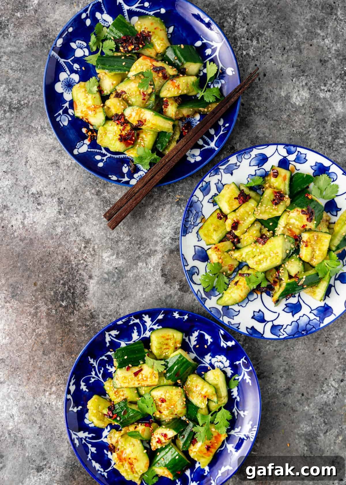 overhead: 3 plated servings of Chinese cucumber salad, one with set of chopsticks