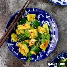 overhead image: smashed cucumber salad and chopsticks on royal blue and white plate