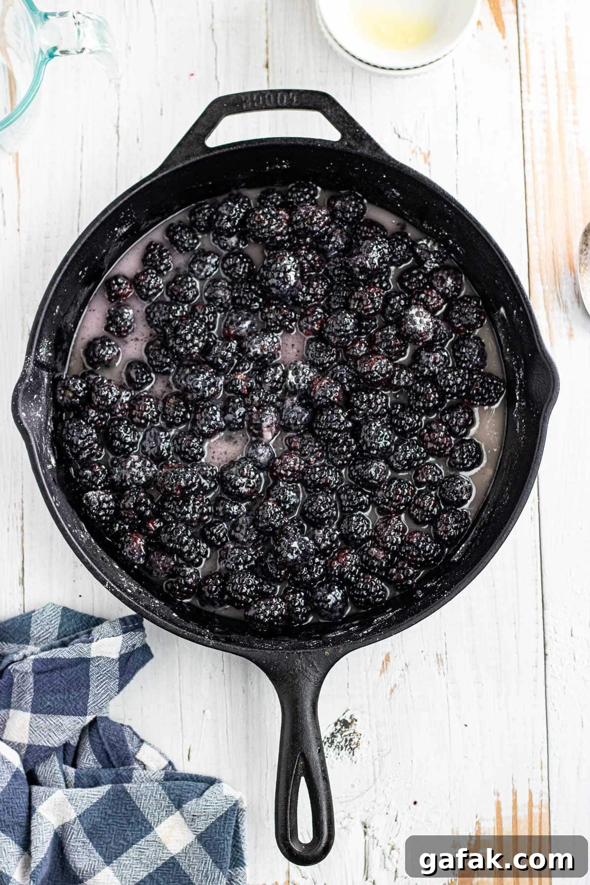 Simmering the blackberries and sugar in the skillet with butter, water, and vanilla.