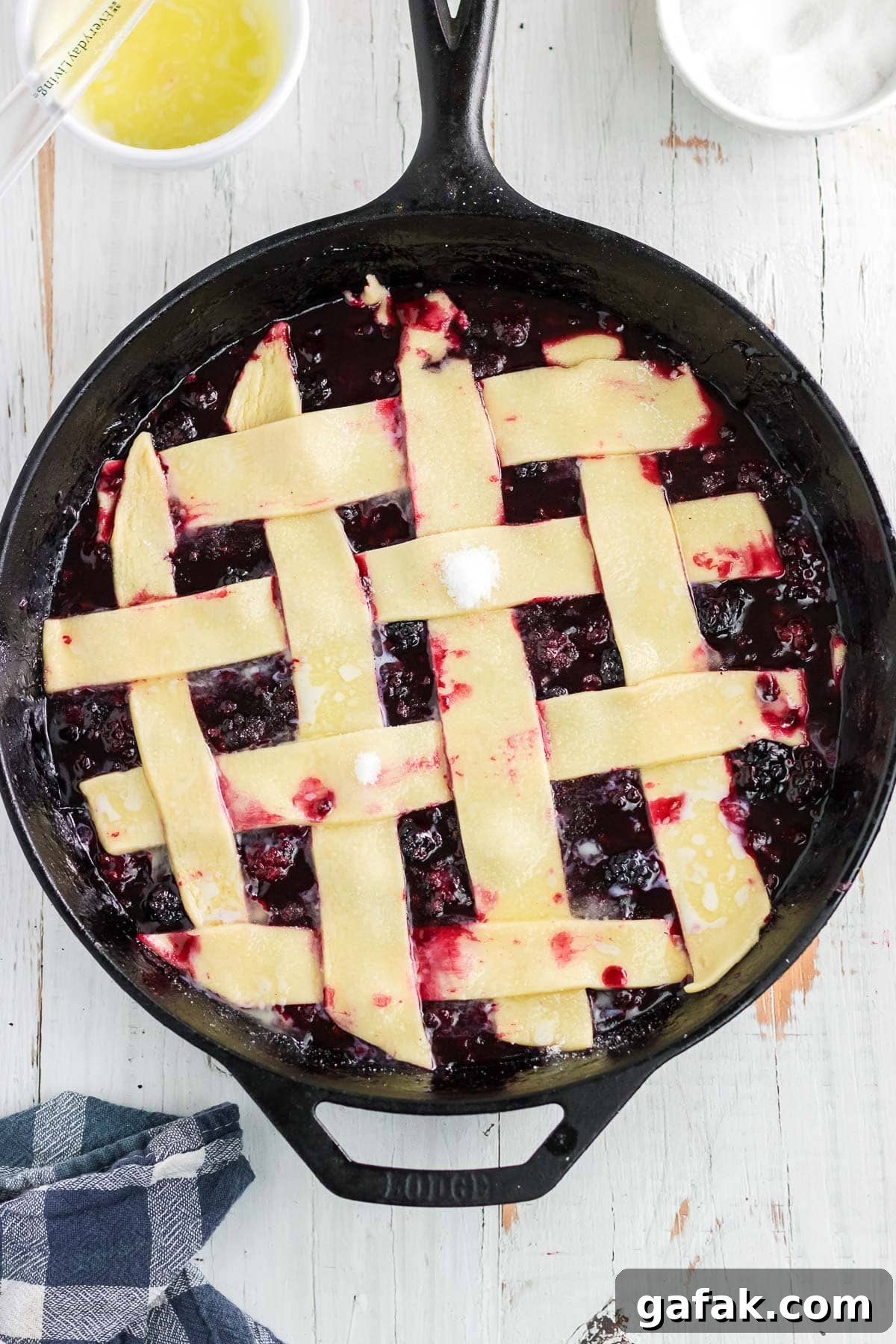 The unbaked pie crust strips arranged in a lattice pattern over the blackberry cobbler.