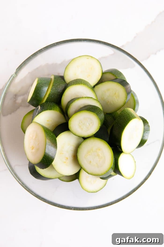 Cheesy Zucchini Casserole with Garlic and Herbs 4 Glass bowl filled with sliced zucchini.