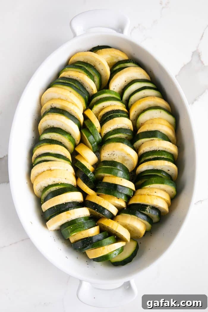 Cheesy Zucchini Casserole with Garlic and Herbs 5 Oval-shaped casserole dish filled with rows of sliced zucchini and yellow squash.