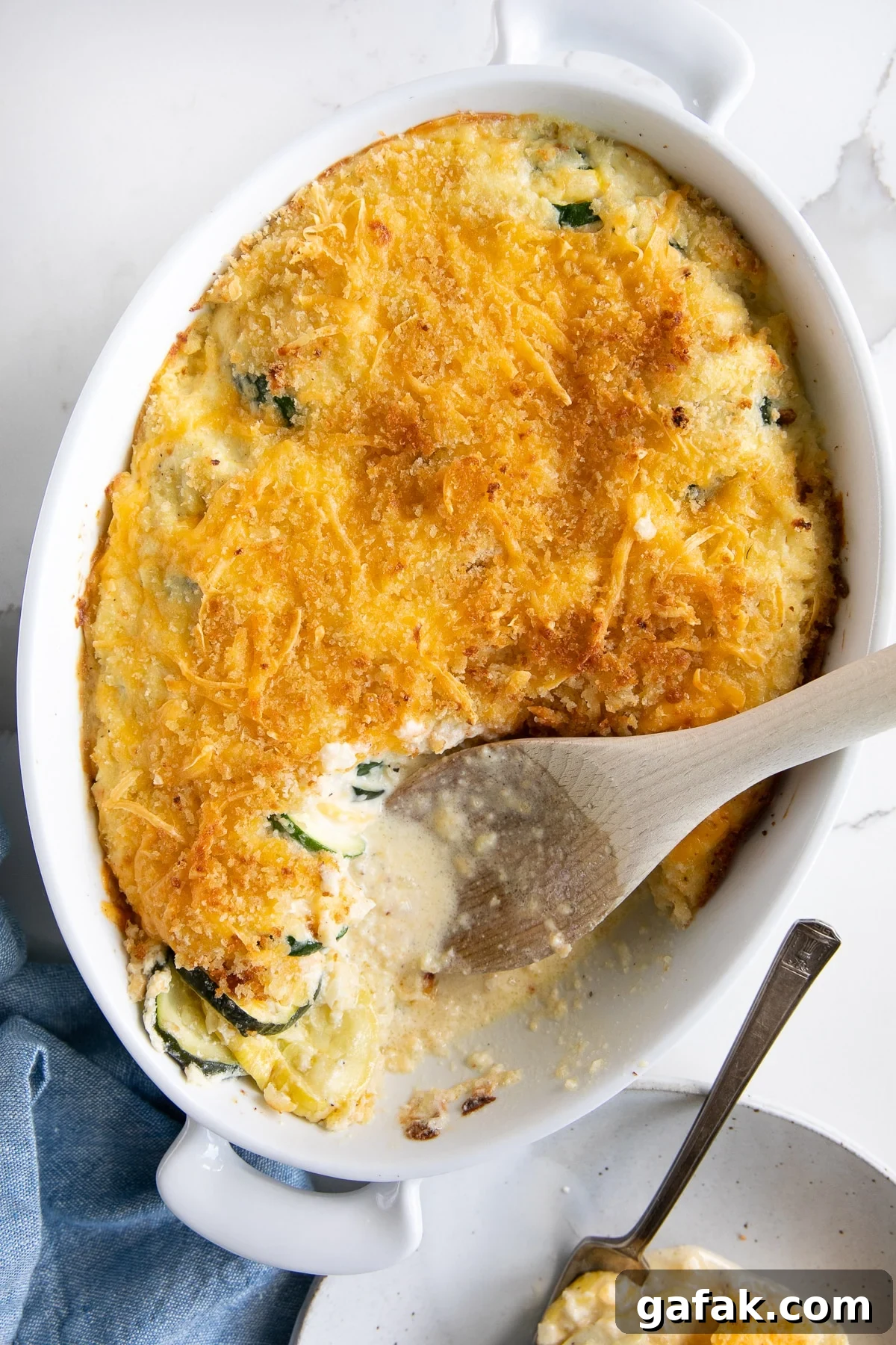 Cheesy Zucchini Casserole with Garlic and Herbs 8 White baking dish filled with baked zucchini casserole topped with panko breadcrumbs and shredded melted cheese.