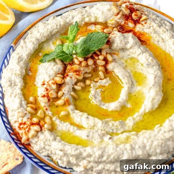 Fatteh with Pita, Hummus, and Creamy Yogurt Bowl 12 Mutabal on a plate with fresh mint and toasted pine nuts