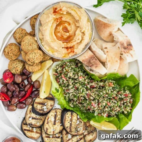 Fatteh with Pita, Hummus, and Creamy Yogurt Bowl 22 Hummus, falafel, tabbouleh, and grilled eggplant on a plate.