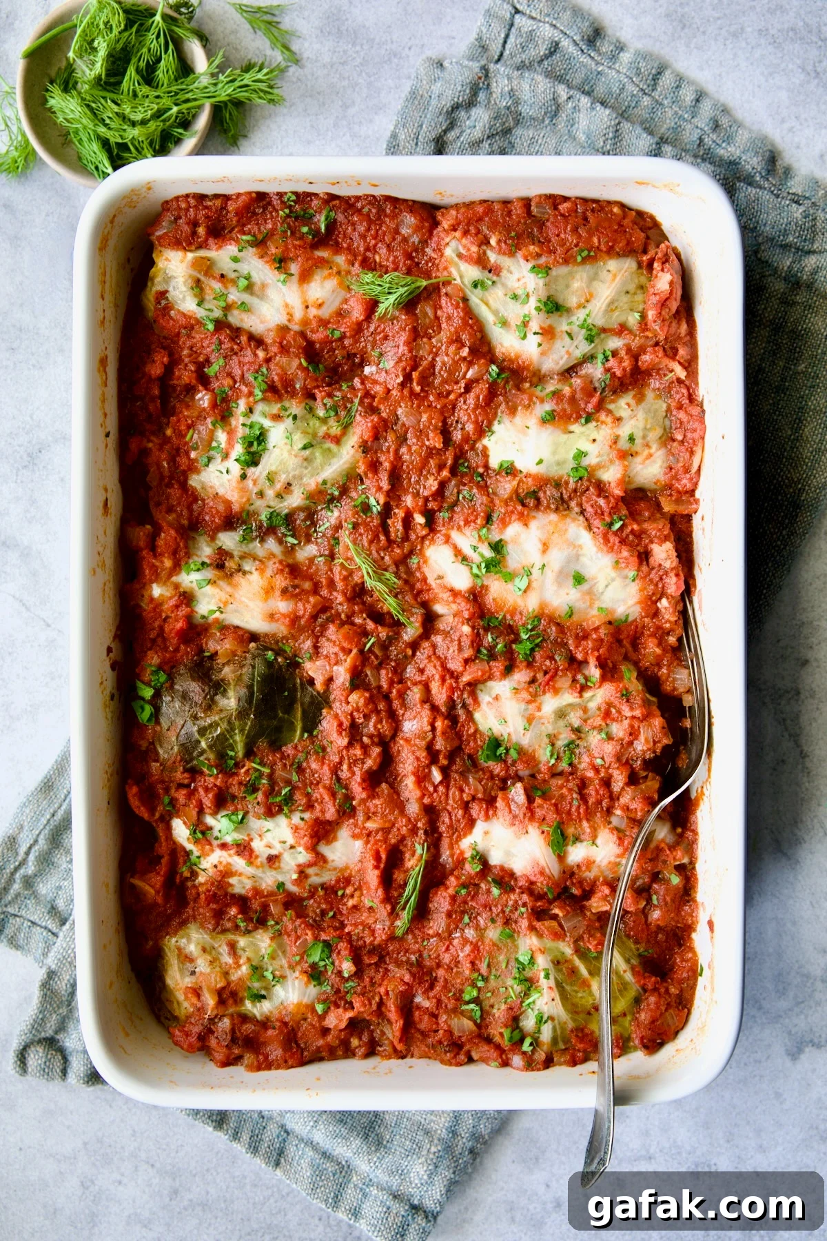 Baking dish full of Polish Stuffed Cabbage on blue napkin after being baked.
