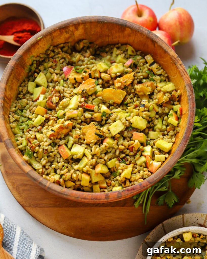 serving homemade fall farro apple salad with roasted squash, parsley, pecans and more next to smoked paprika, fresh parsley, and apples on a serving table.