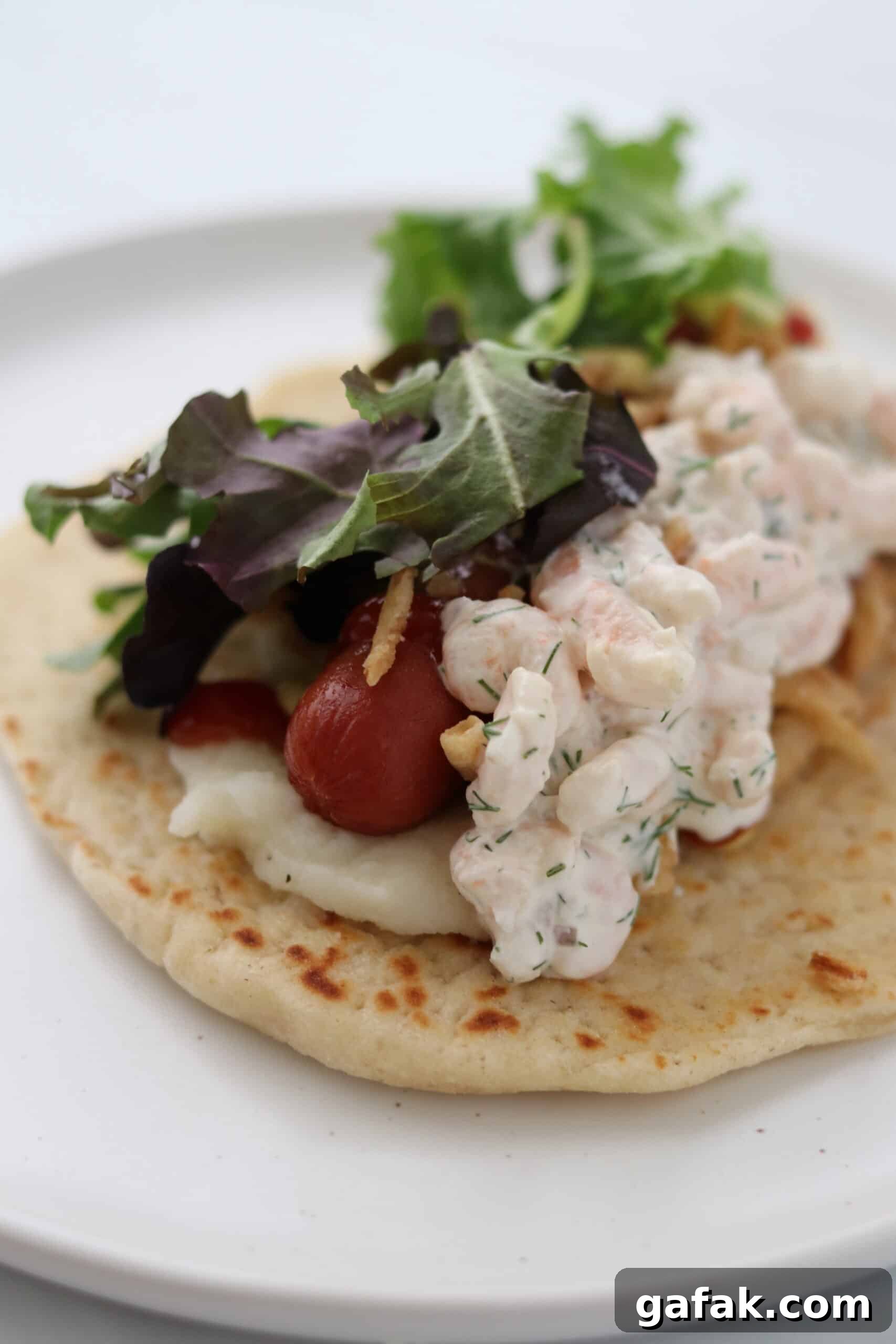 Shrimp salad on flatbread with mashed potatoes, a hot dog and lettuce.