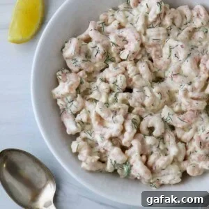 Close up of a bowl of Skagenröra (Swedish Shrimp Salad) next to a spoon and lemon wedge.