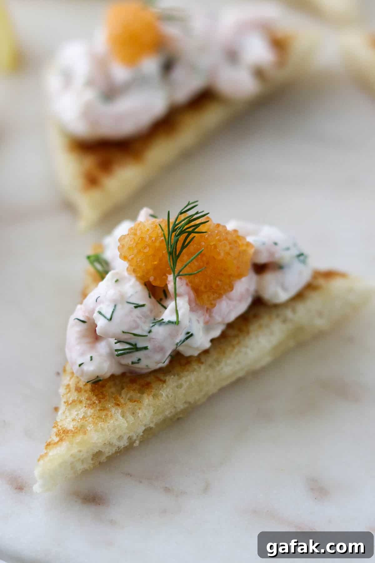 Skagenröra on top of toasted white bread with caviar on top.