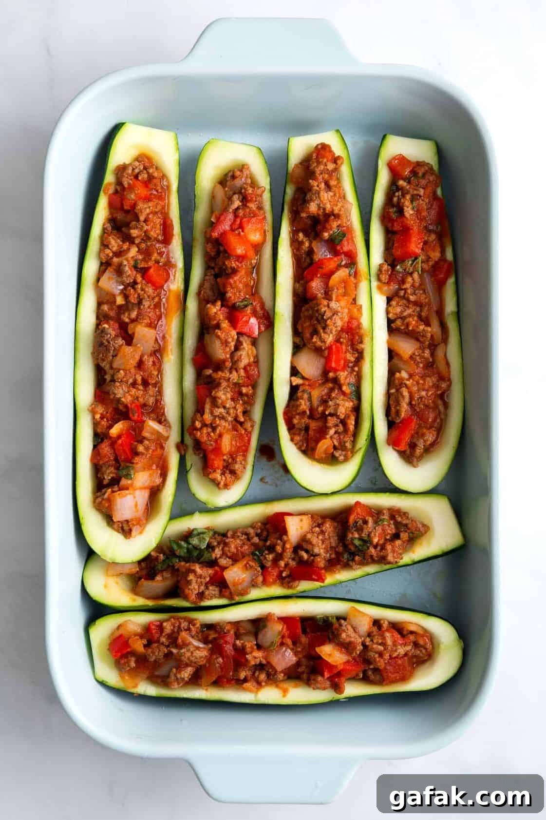 stuffed zucchini lined in a blue 9x13 casserole dish.