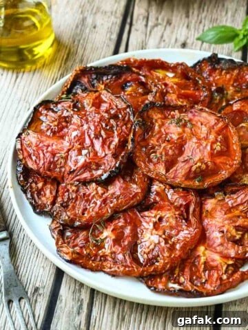 Roasted Beefsteak tomato slices on a white plate with a fork to the left.