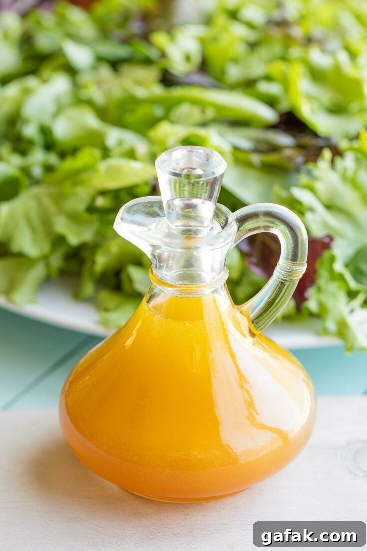 Vinaigrette in stoppered cruet with large platter of salad behind.