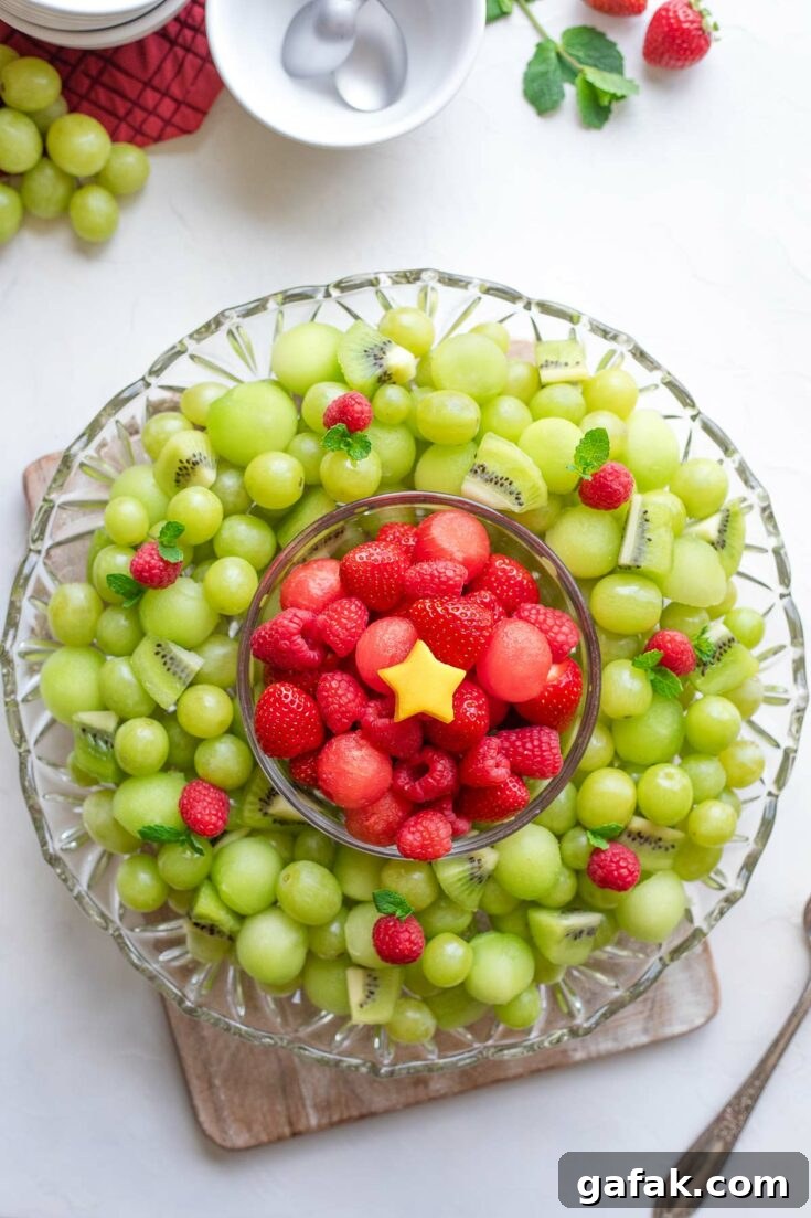 Completed Christmas fruit platter, with small mango star at the very center; extra fruit, bowls and spoons nearby.