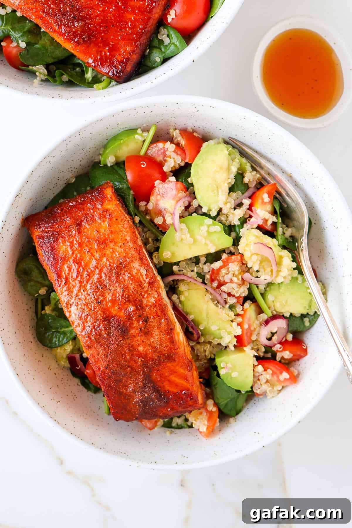 Paprika salmon filet in a bowl with avocado quinoa salad.