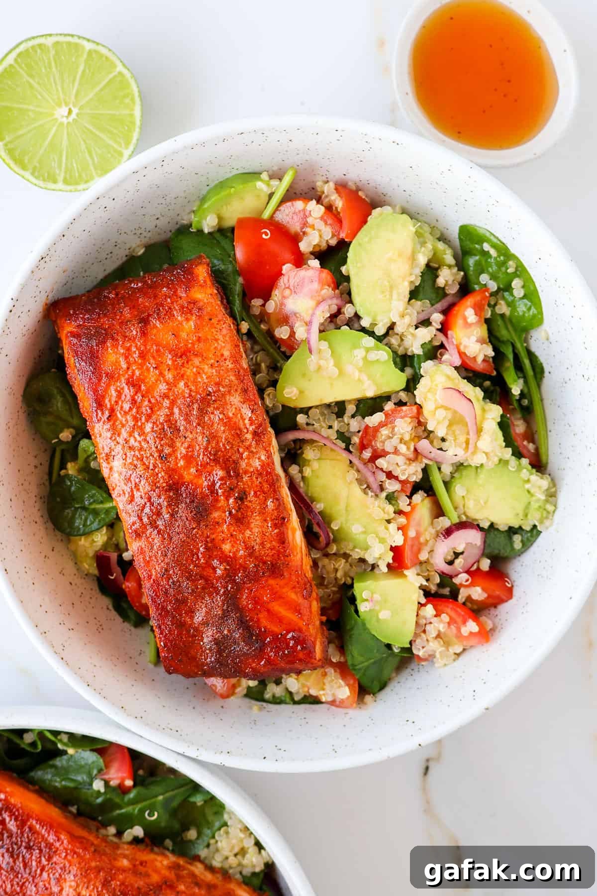 Paprika salmon filet in bowls with avocado quinoa salad.