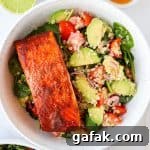 Paprika salmon filet in bowls with avocado quinoa salad.