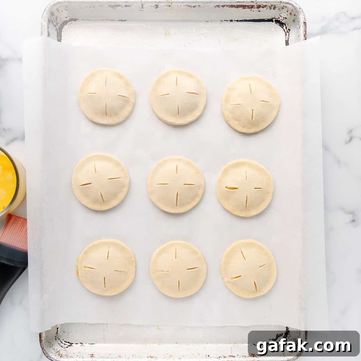 Mini Pumpkin Hand Pies: Flaky Autumn Pastry Recipe 12 Sealed hand pies on a parchment paper lined pan.