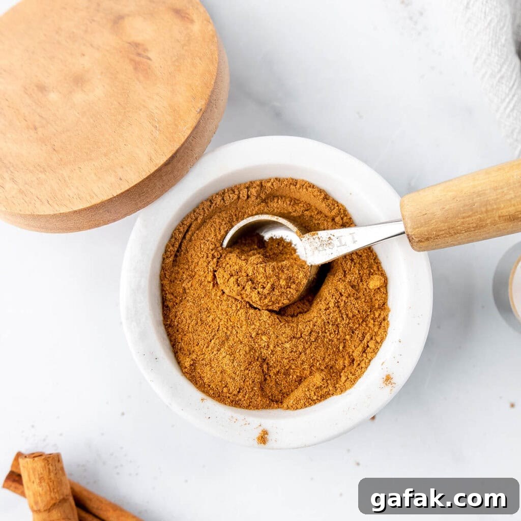 Mini Pumpkin Hand Pies: Flaky Autumn Pastry Recipe 19 A white dish with a measuring spoon scooping spices.